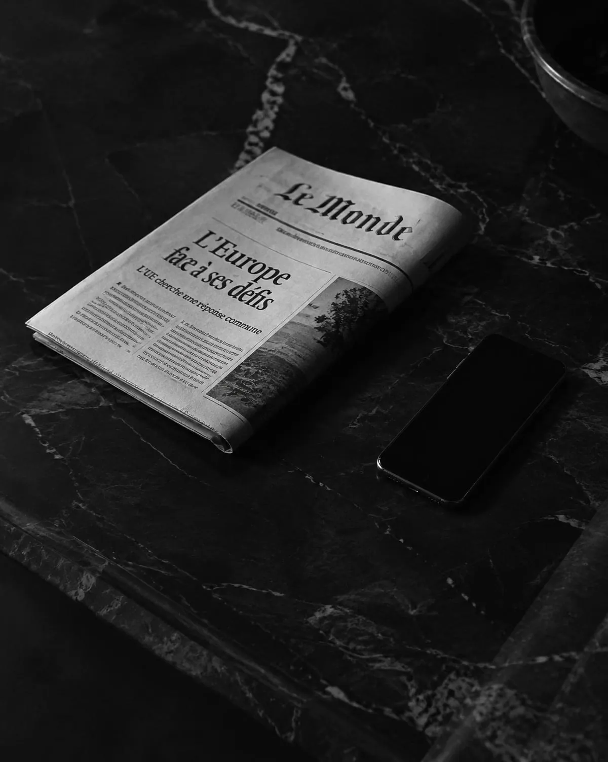 Newspaper and phone on black marble